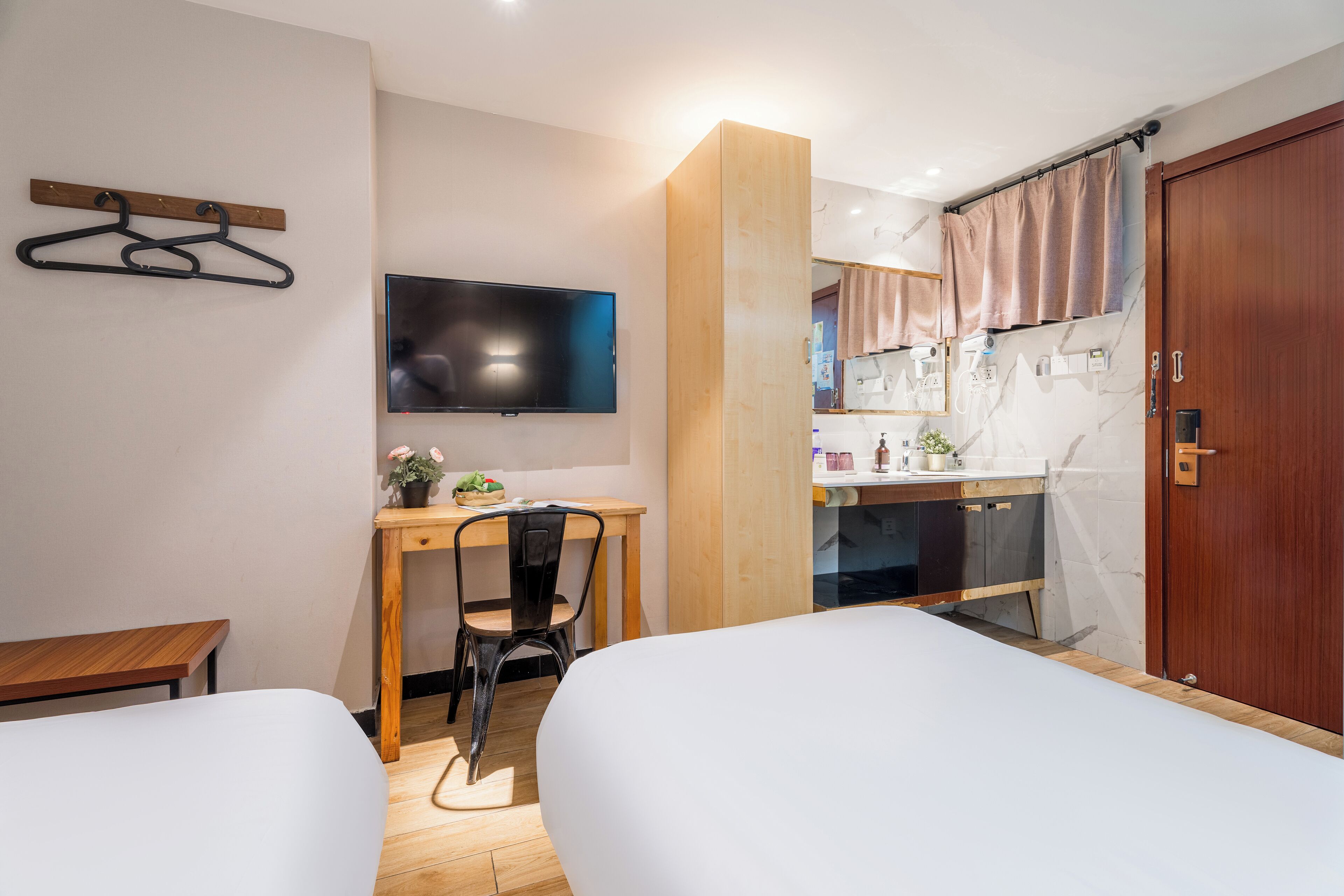 Habitación de hotel con dos camas, un escritorio, una silla, un televisor y una kitchenette.
