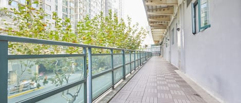 A corridor with a tiled floor, glass railings, and a view of tall buildings.