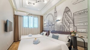 Habitación de hotel con dos camas, un televisor de pantalla plana, un escritorio con silla y un mural con el horizonte de una ciudad.