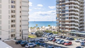 A high-rise building with multiple balconies overlooking a parking area and a beach. - Bacana 3-3 (Benidorm)