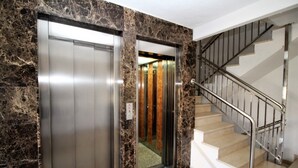 An elevator and a staircase with a metal railing. - Bacana 3-3 (Benidorm)