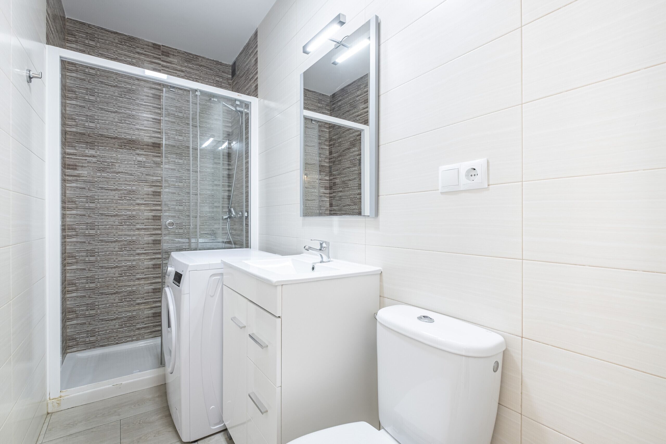 A modern bathroom with a glass-enclosed shower, a white sink, and a toilet.