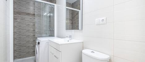 A modern bathroom with a glass-enclosed shower, a white sink, and a toilet.