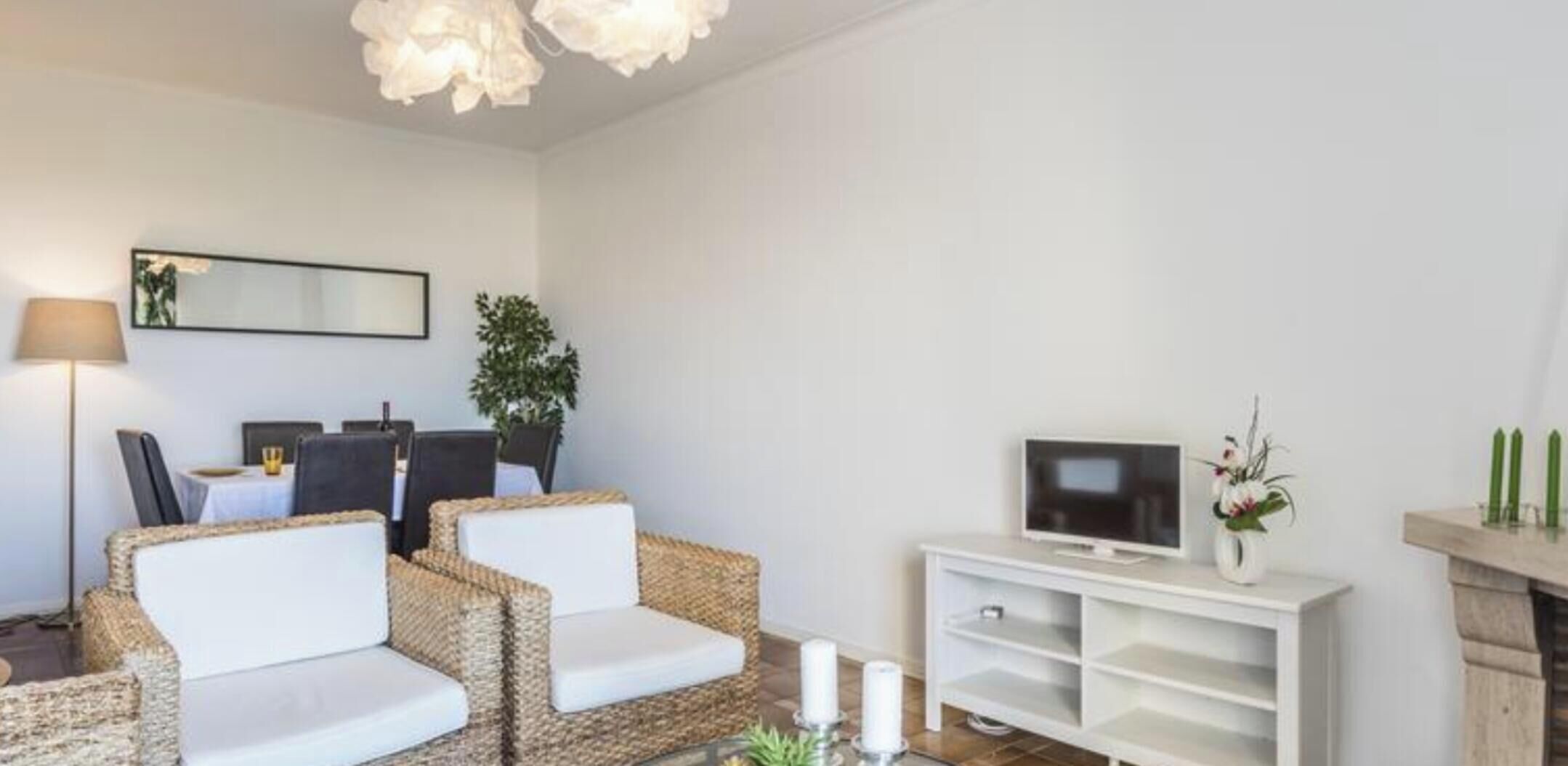 A modern living room with a sofa set, a television, a fireplace, and a dining area.