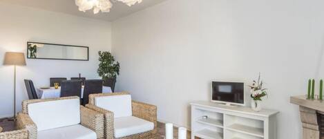 A modern living room with a sofa set, a television, a fireplace, and a dining area.