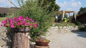 A garden area with a wooden stump and a metal planter with pink flowers. - Kramerhof (Taufkirchen)
