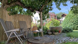 A garden patio with a table and chairs, a large planter, and a stone pathway. - Kramerhof (Taufkirchen)