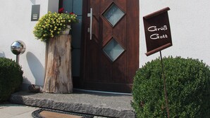 A building with a wooden door, a sign above the door, and a sign to the right. - Kramerhof (Taufkirchen)