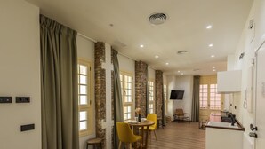 A modern hotel room with a dining area, a TV, and a kitchenette. - Chinitas 17 IIi - iloftmalaga (Málaga)