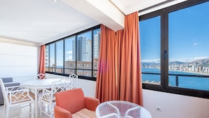 A balcony with a table, chairs, and a view of a cityscape and water.