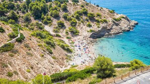 A coastal area with a beach, rocky terrain, and a clear view of the sea.