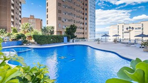 A swimming pool surrounded by greenery and tall buildings.
