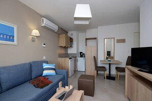 Ein gemütlicher Wohnbereich mit Sofa, Essplatz, Küchenzeile und Fernseher.