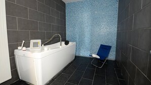 Baño con bañera, asiento de ducha y pared con azulejos.