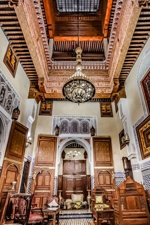 An ornate interior with intricate woodwork, a large chandelier, and traditional furniture.