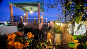 Un espace extérieur aménagé en terrasse, doté d’un coin salon abrité, d’un escalier et d’un éclairage décoratif.