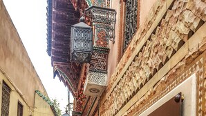 Une rue étroite bordée d’un immeuble sur lequel on peut voir une enseigne indiquant « Riad Mama H&K, maison d’hôtes et restaurant ».