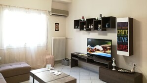 A modern living room with a flat-screen TV, a sofa, a coffee table, and decorative shelves.