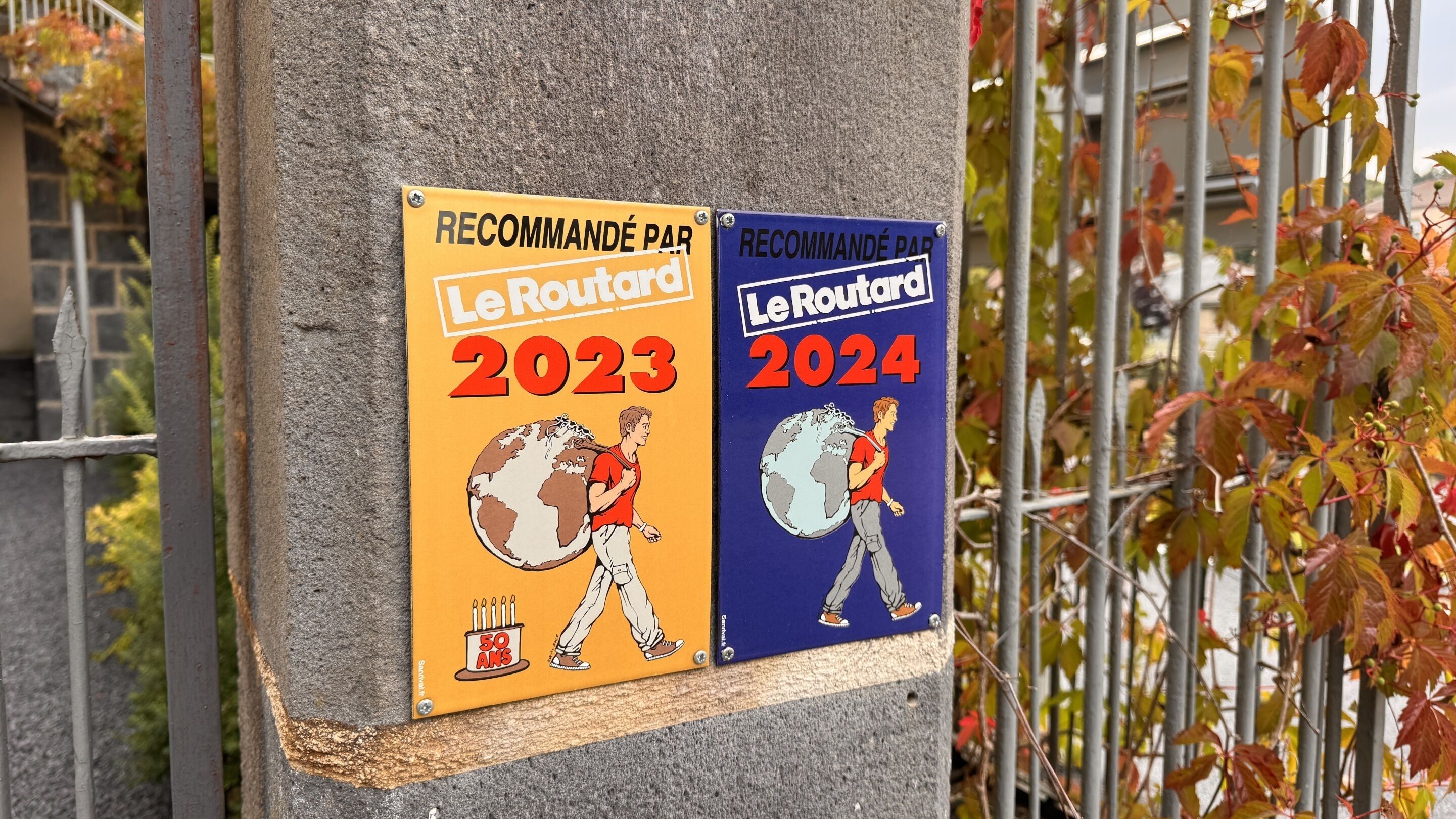 Two plaques on a pole with 'RECOMMANDÉ PAR Le Routard 2023' and 'RECOMMANDÉ PAR Le Routard 2024' text.