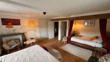 A cozy bedroom with a bed, a small table, a chair, a fireplace, and a door leading to another room.