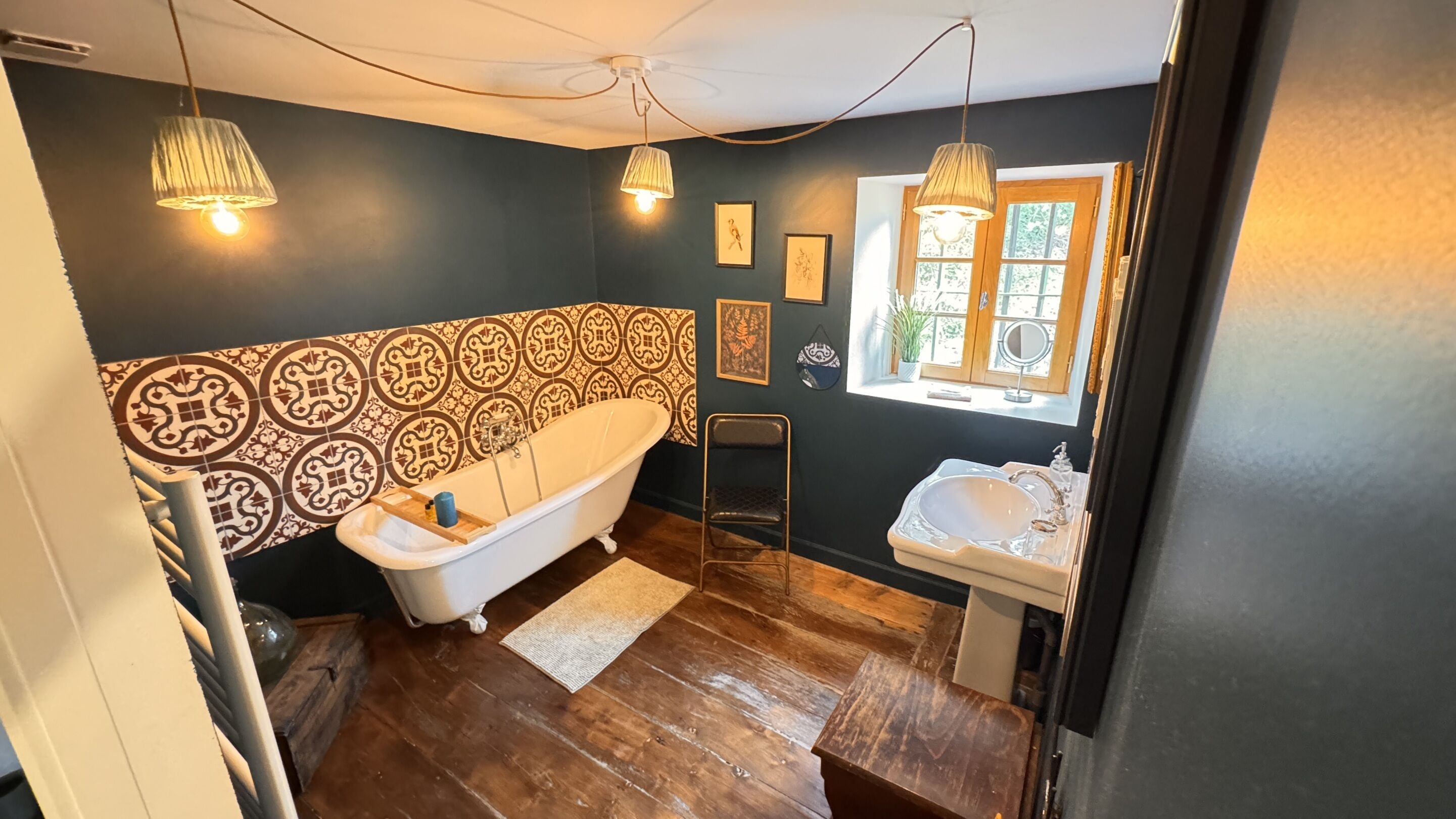 Un bagno con vasca, lavandino, piastrelle decorate e una finestra con vista.