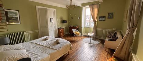 Una habitación con cama, una silla, una mesa y un radiador.