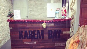 A reception desk with 'KAREM BAY' signage, a small Christmas tree, and a wooden tree trunk decoration. - Hotel Karem Bay (Koumac)