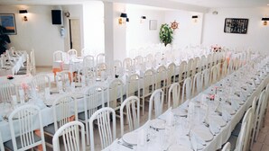 A banquet hall with long tables set for a formal event, white chairs, and a nautical-themed wall decoration. - Hotel Plaça Vella (Sant Carles de la Rapita)