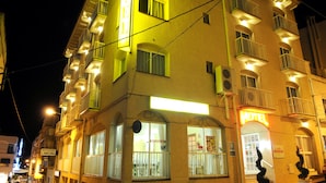 A hotel with multiple balconies, a restaurant sign, and a well-lit facade at night. - Hotel Plaça Vella (Sant Carles de la Rapita)