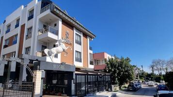 Un hotel con fachada moderna, una estatua de un caballo y una entrada porticada.
