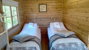 A cabin room with two beds, wooden walls, a window, and a framed picture on the wall. - Hótel Stadarborg (Fjardabyggd)