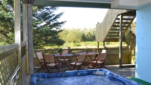A hot tub with a wooden deck, outdoor furniture, and a wooden staircase. - Hótel Stadarborg (Fjardabyggd)