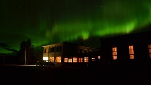 A building with multiple windows and a lit exterior at night. - Hótel Stadarborg (Fjardabyggd)