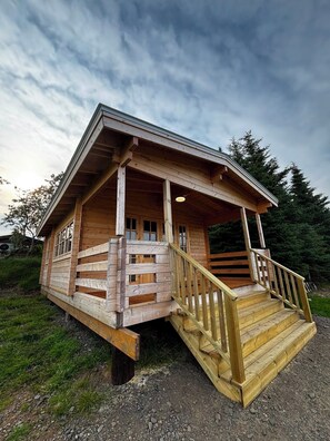 A wooden cabin with a porch and a staircase leading to the entrance. - Hótel Stadarborg (Fjardabyggd)