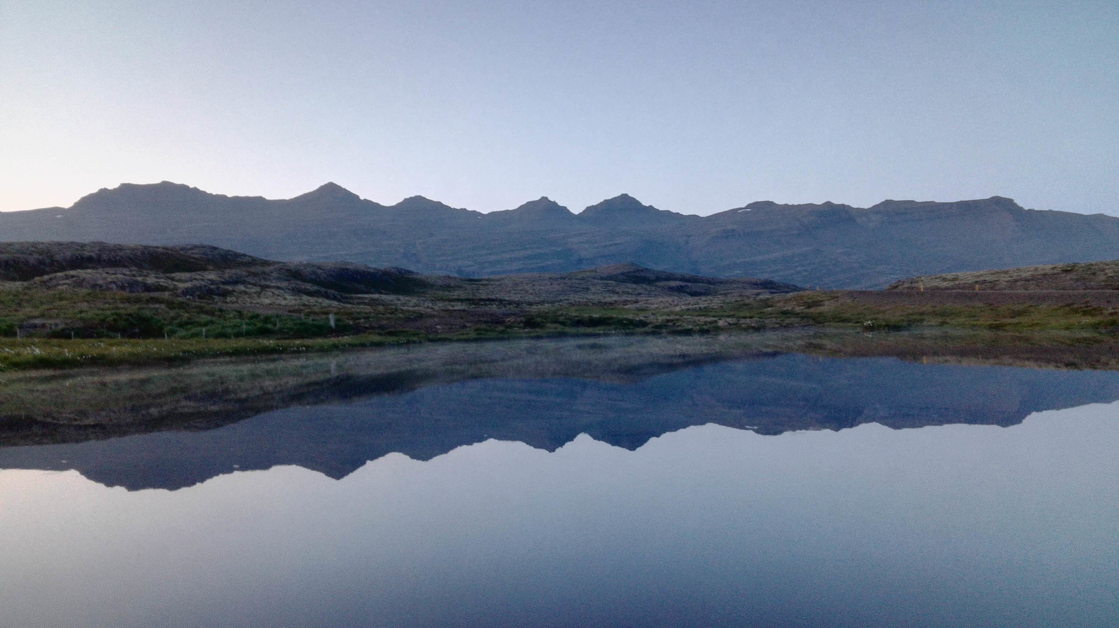 A mountain landscape with a calm lake reflecting the peaks.
