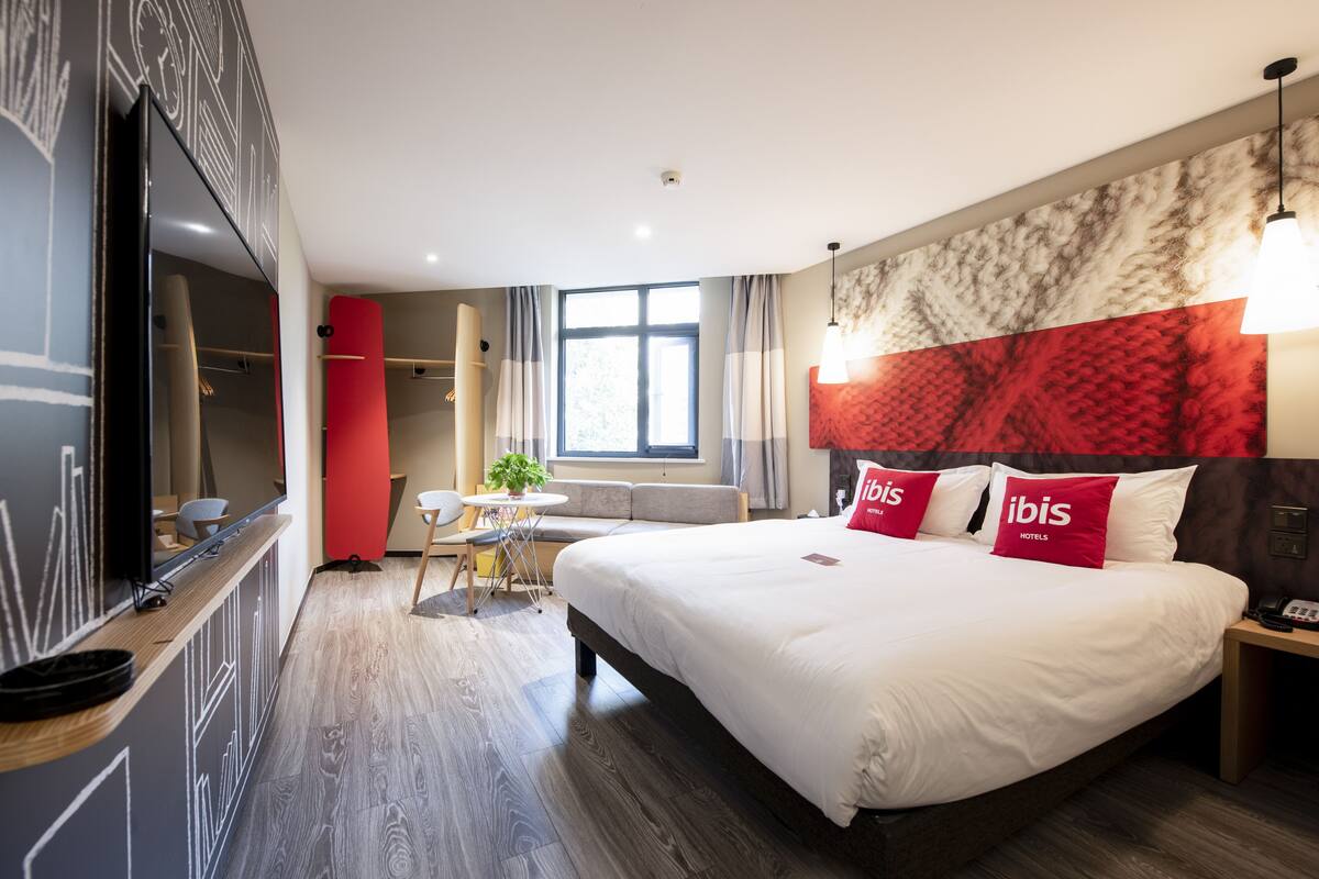 Une chambre d’hôtel moderne avec un grand lit, une télévision, un bureau et une fenêtre.
