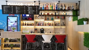 A bar area with a menu board, shelves of liquor bottles, and two red bar stools. - Ibis Hangzhou Future Sci-tech City Hotel (Hangzhou)