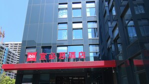 A modern hotel building with a red awning and a large glass entrance. - Ibis Hangzhou Future Sci-tech City Hotel (Hangzhou)