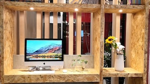 A workspace with a computer monitor, bookshelves, a chair, and potted plants. - Ibis Hangzhou Future Sci-tech City Hotel (Hangzhou)