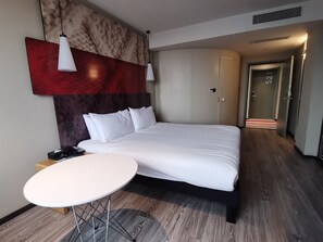 A modern hotel room with a large bed, a round table, and a red abstract wall art piece. - Ibis Xi'an Jianzhang Road Fengdong New Area Hotel (Xi'an)