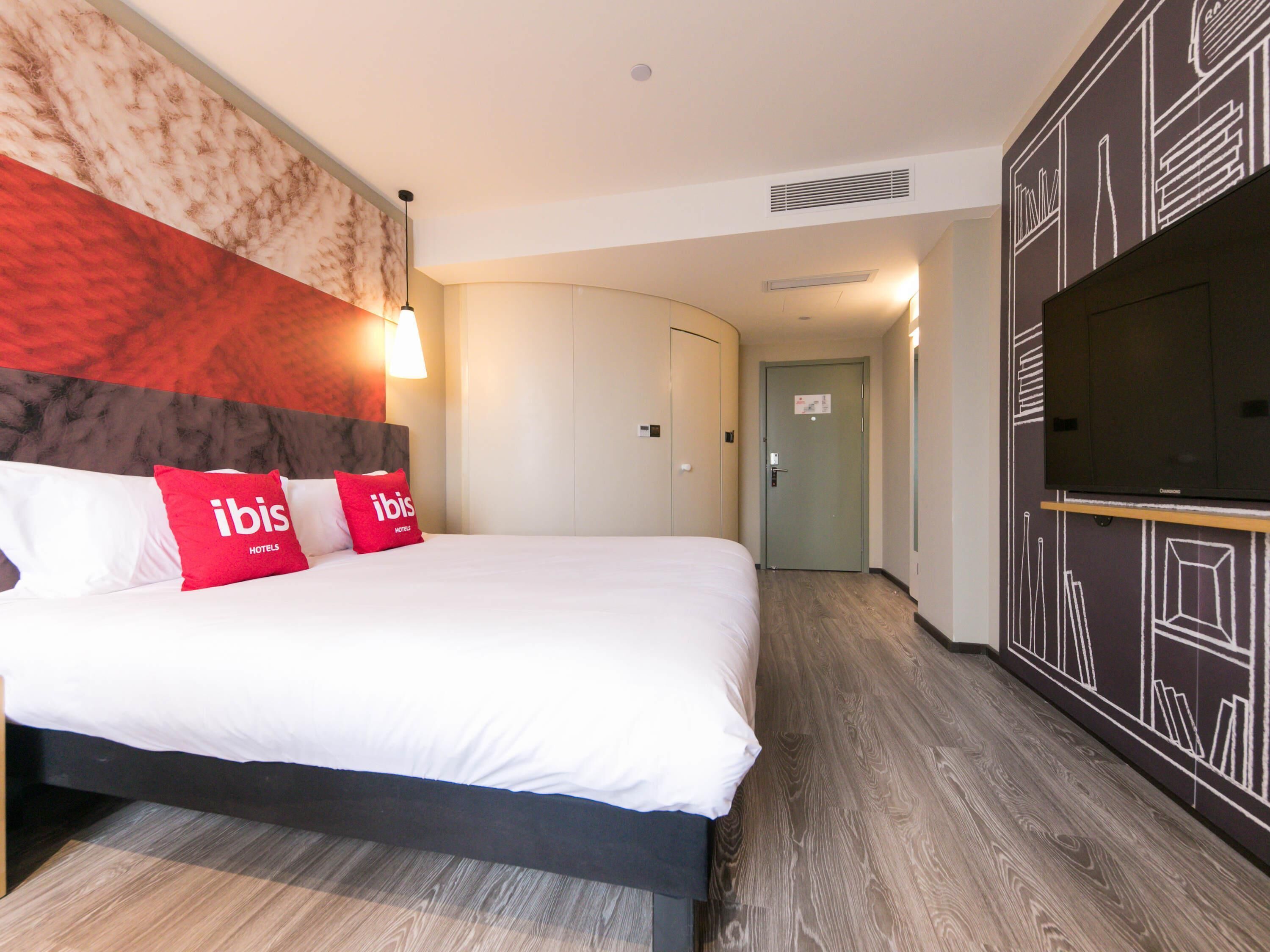 Una habitación de hotel con cama, televisor, armario y puerta.