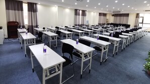 A conference room with rows of tables and chairs, equipped with water bottles, a podium, and a projector. - Ibis Xi'an Jianzhang Road Fengdong New Area Hotel (Xi'an)