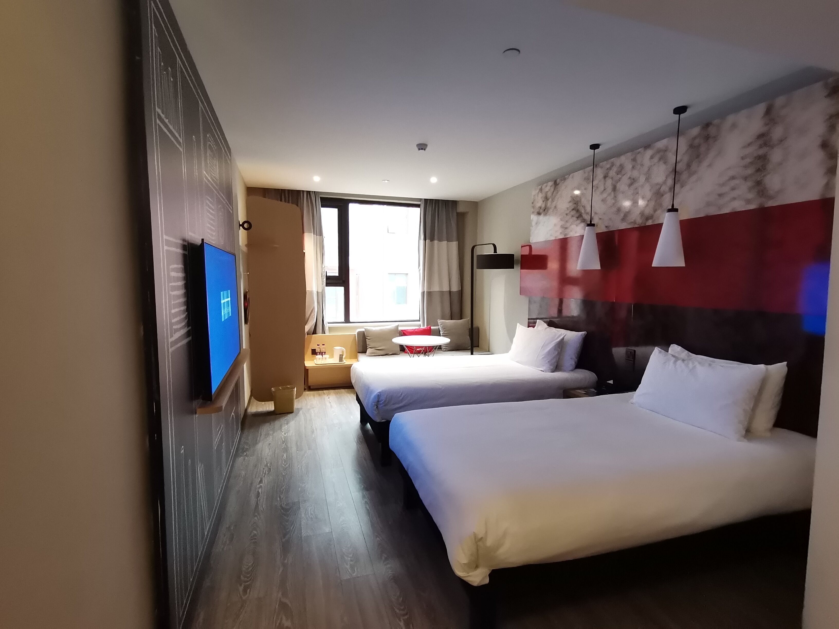 Hotelkamer met twee bedden, een televisie, een bureau met stoel en een raam met gordijnen.