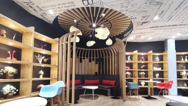 A modern interior with a central seating area, wooden shelves with decorative items, and a ceiling with artistic designs. - Ibis Xi'an Jianzhang Road Fengdong New Area Hotel (Xi'an)