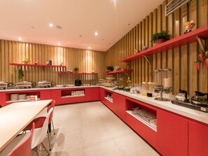 Una cocina moderna con armarios rojos, encimera blanca y diversos electrodomésticos.