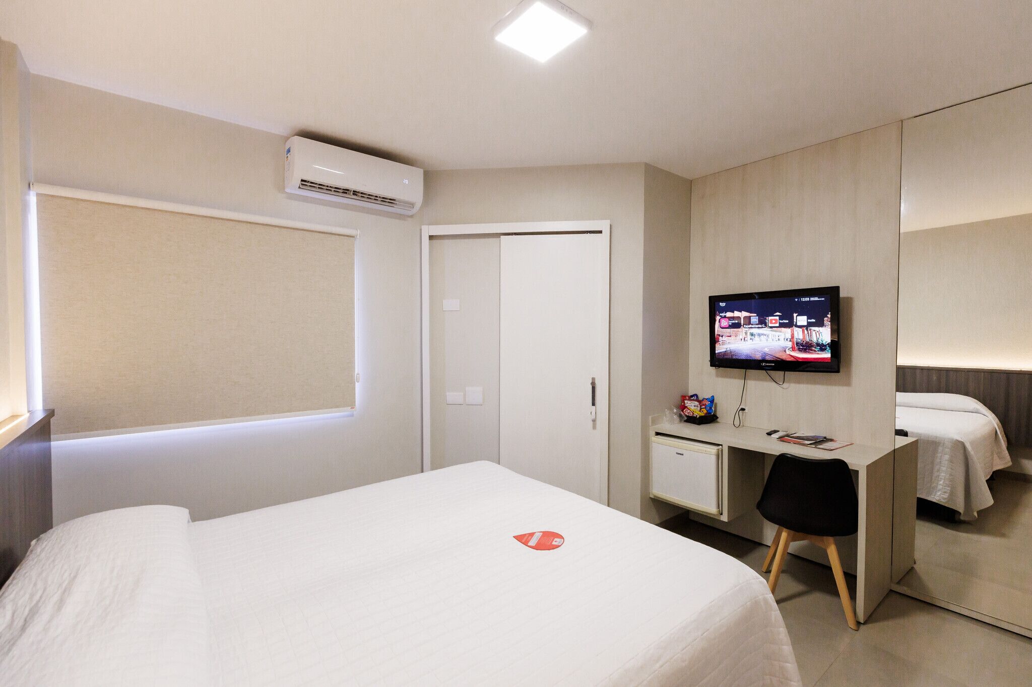 Een hotelkamer met een bed, een bureau met stoel, een televisie en een kledingkast.