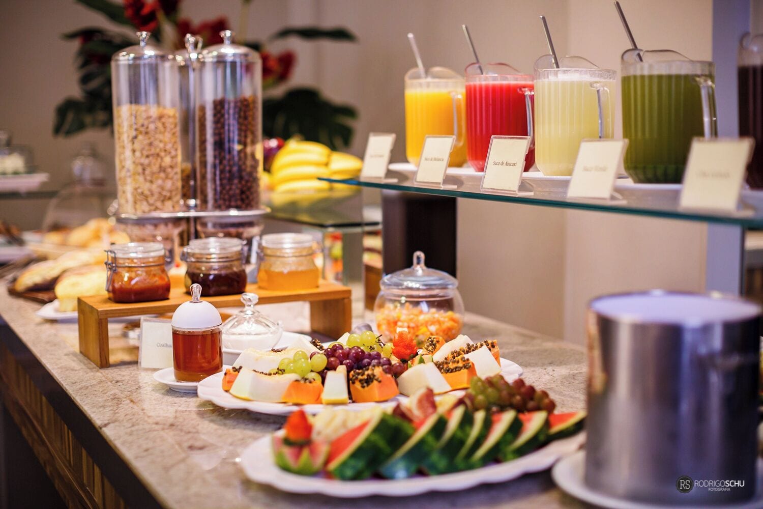 Un bufé con diversos alimentos y bebidas, incluyendo frutas, quesos y una variedad de refrescos.