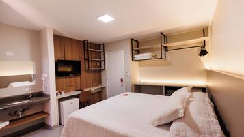 Una habitación de hotel con cama, escritorio, televisor y baño.