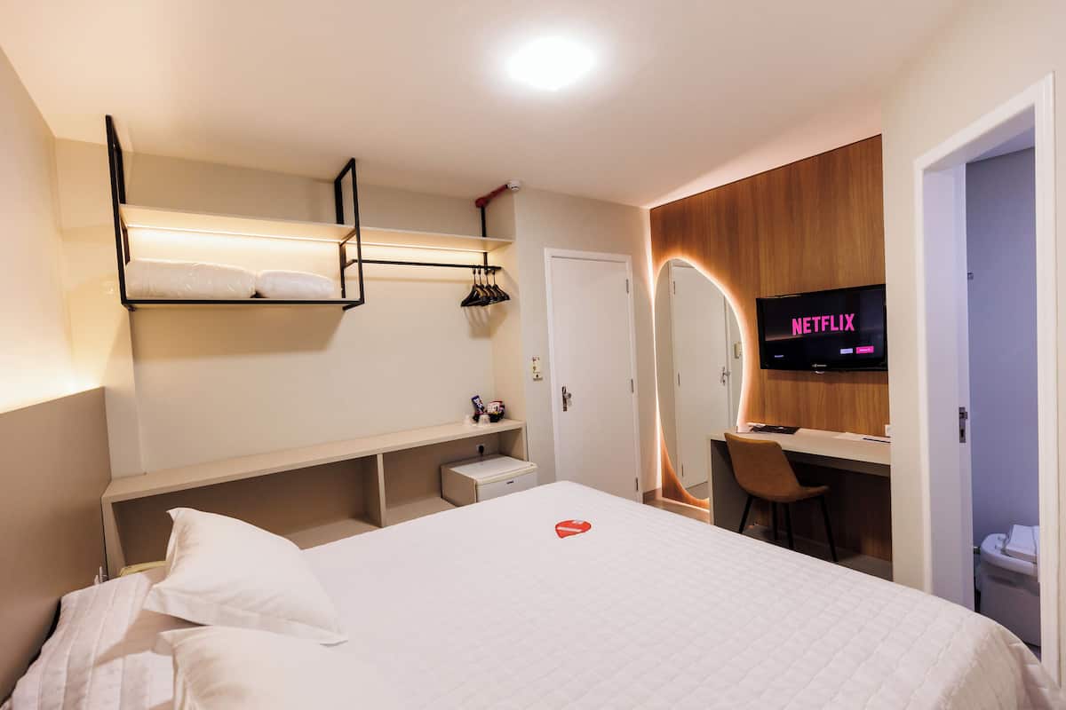Une chambre avec un lit superposé, un bureau, une chaise, une télévision et une petite salle de bain.