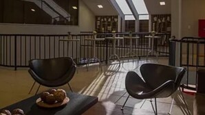 Un vaste espace intérieur doté d’un haut plafond, de verrières et de chaises noires au design moderne.